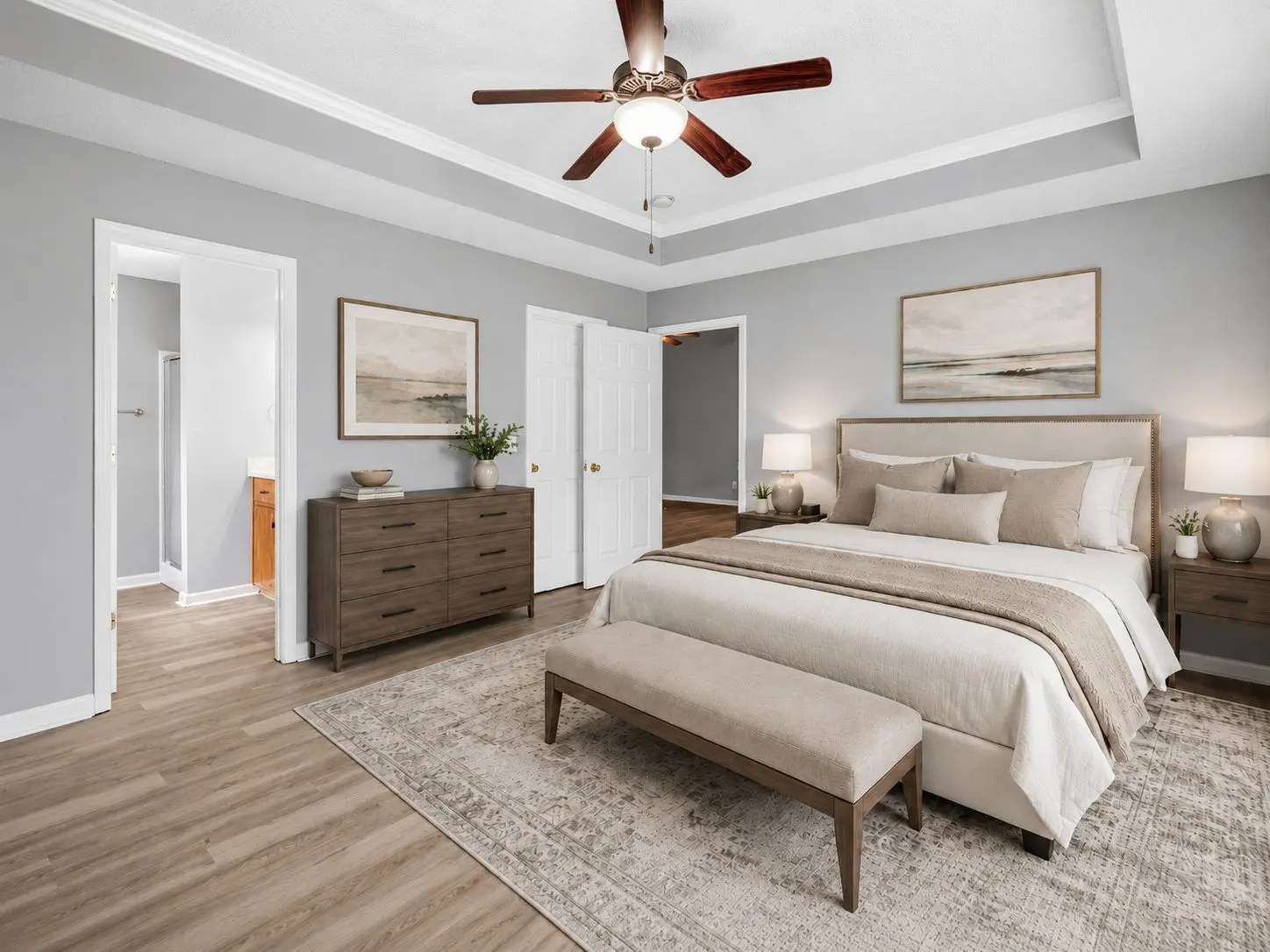 Same primary bedroom after virtual staging with bed, dresser, and bench